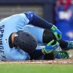 Blue Jays' George Springer lying on field holding his left leg in pain after injury during game