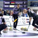 Curlers sliding stones on ice as teammates sweep vigorously to guide the stone during a competitive match
