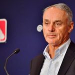MLB commissioner speaking at a podium during a press conference on proposed salary cap